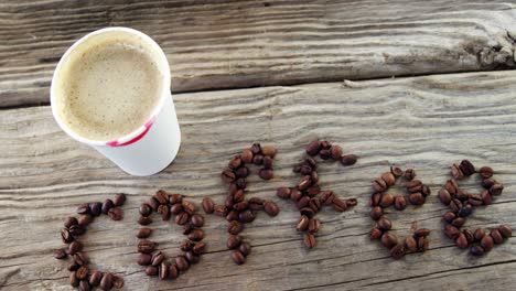 disposable cup and coffee written with coffee beans