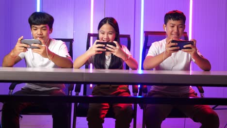 team of asian esport gamers playing in competitive video games on a cyber games tournament by mobile phone