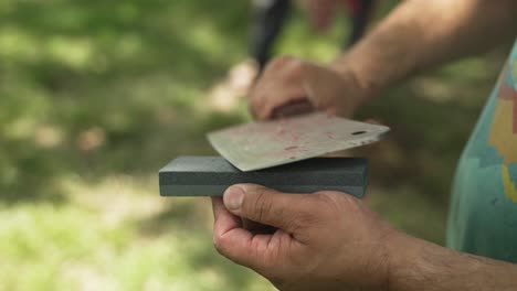 Middle-eastern-man-sharpens-a-blade-being-used-to-cut-sheep-meat-to-eat-in-celebration-of-Muslim,-religious-holiday-Ramadan,-Eid-al-Adha-or-Eid-al-Fitr-in-cinematic-slow-motion