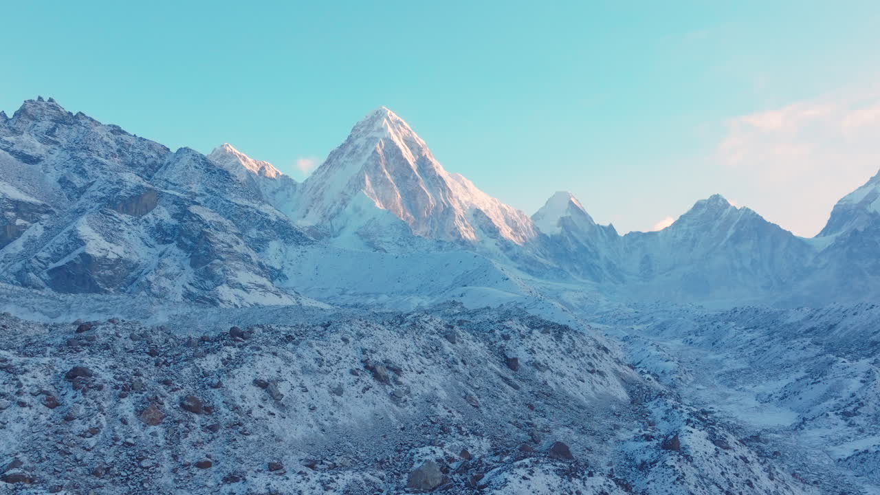 Aerial reveal drone shot of Everest Base Camp trek in Khumbu, Nepal. Morning snowfall uncovers Mount Pumori, Lobuche, and Nuptse as sunrise reflects on the Himalayas, creating a majestic travel scene
