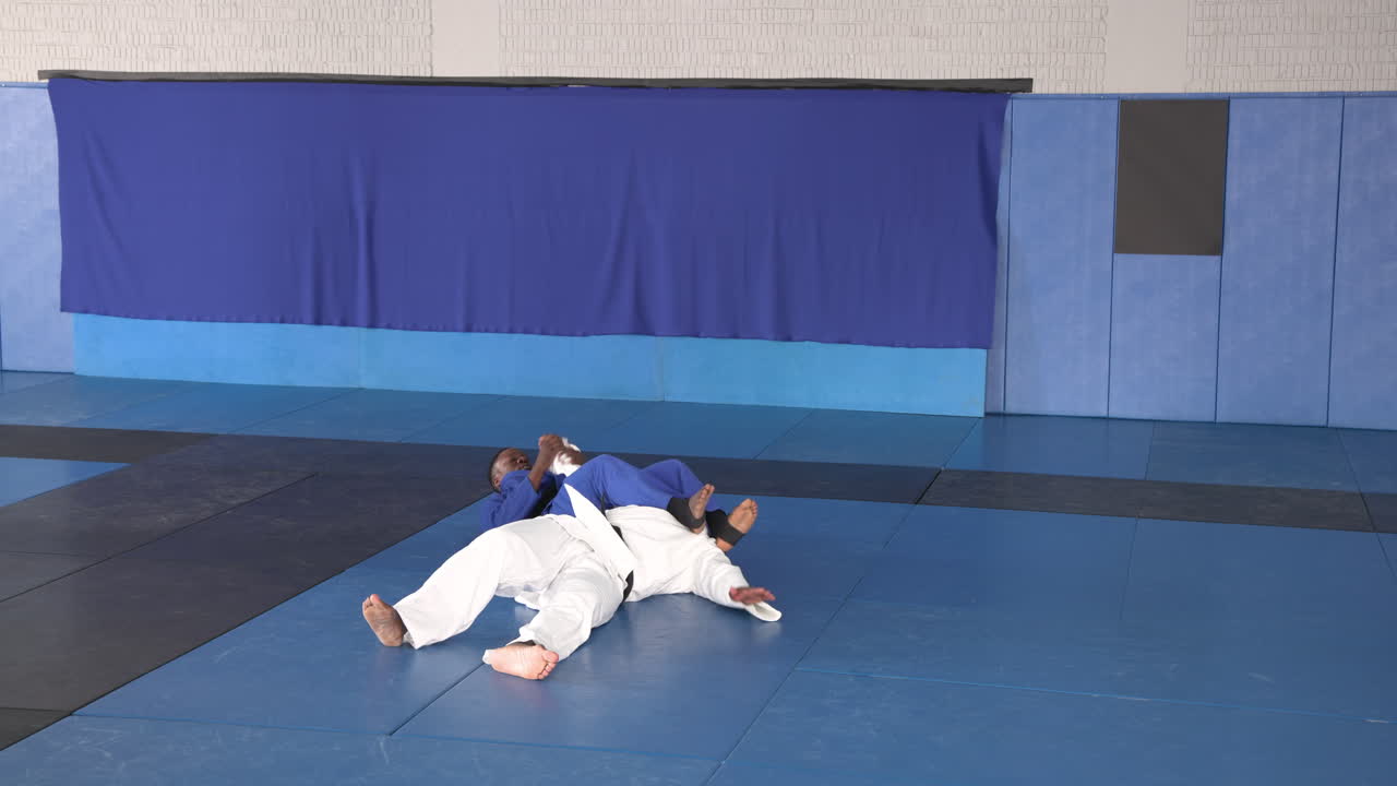 Practicing judo, two men in martial arts uniforms sparring on mat