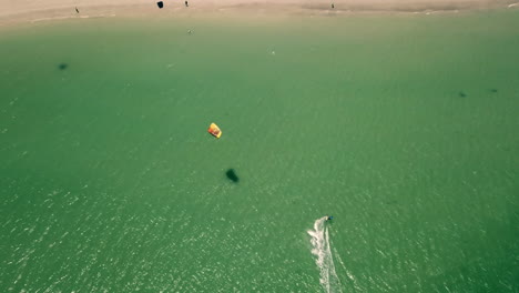 high altitude top down drone shot of kite surfer in turquise atlantic ocean approaching langebaan beach in south africa on perfect sunny weather in natural daylight