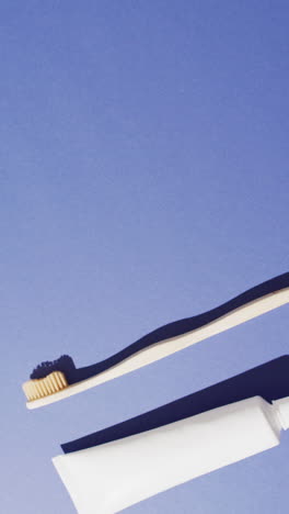 vertical video of toothpaste and toothbrush on blue background with copy space