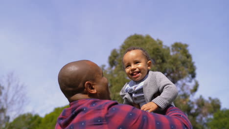 Padre-Afroamericano-Vomitando-A-Su-Hijo-Al-Aire,-Niño-Riendo