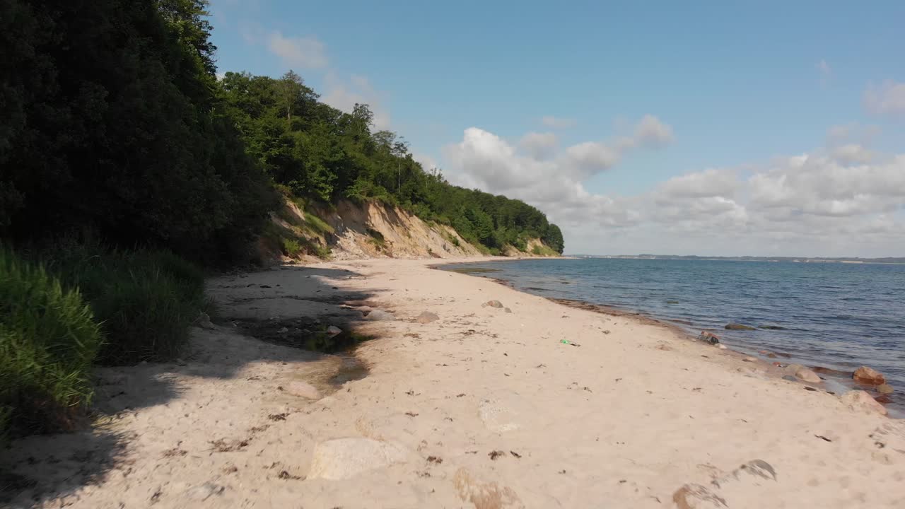 Wunderschöner Strand in Norddeutschland, Schleswig-Holstein, genannt Noer Strand an der Ostsee. Etwas Müll am Strand. Drohne fliegt in geringer Höhe neben der Klippe vorwärts.
