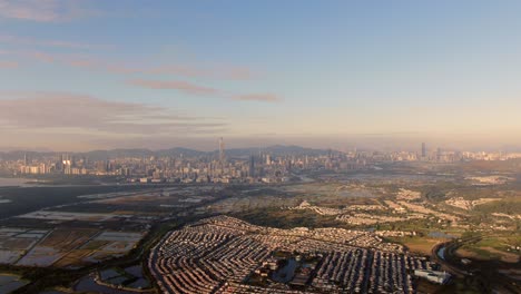 hong kong and shenzhen border line over hong kong rural houses with shenhzen skyline in the horizon, aerial view