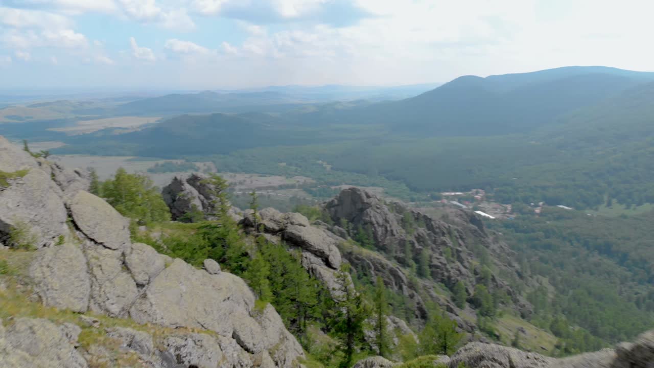 한 젊은 여성이 인상적인 산 절벽의 가장자리에 앉아 있습니다.