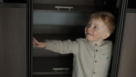 A-little-boy-opens-doors-of-a-closet-and-comes-out-from-there