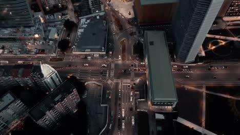 Vehicles-Travelling-At-The-Busy-Road-Near-The-Library-Of-Trees-Garden-Park-And-Botanical-Garden-Surrounded-By-The-High-rise-Buildings-And-Contemporary-Skyscrapers-At-Night-In-Milan,-Italy