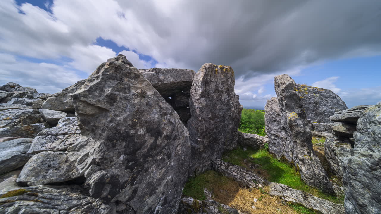 Timelapse de paisagem rural com formação rochosa neolítica em primeiro plano durante um dia ensolarado com nuvens, visto de Carrowkeel, no condado de Sligo, na Irlanda
