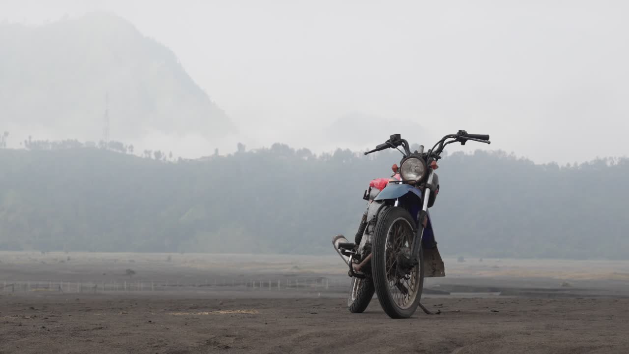 Motorcycle road trip stop on dirt track, low visibility jungle forest background