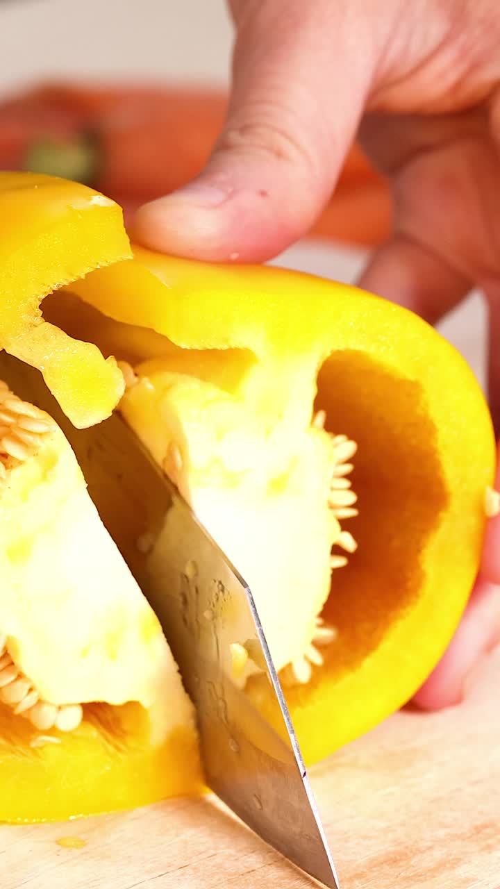 manos cortando pimientos amarillos en una tabla de madera