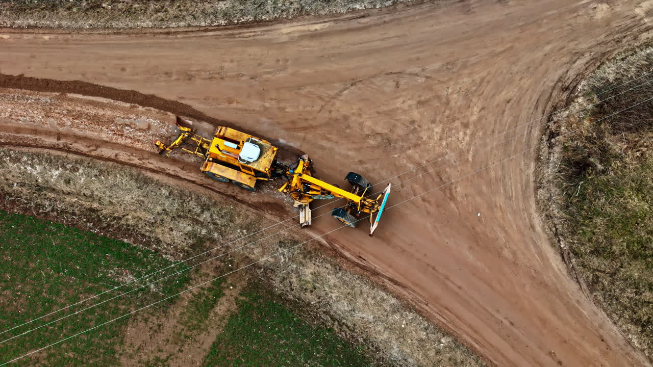 Droneudsigt ovenfra af en traktor med en vejplaner, der anlægger en vej