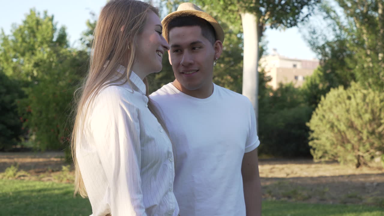 Young couple walking at public park. Happy latin man and Caucasian woman in love