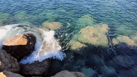 pristine clear sea water crashing against rocky shore during sunny day