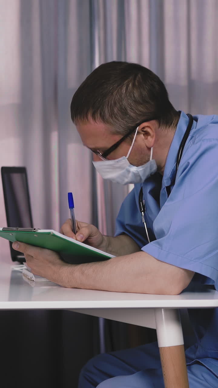 doctor in light blue uniform and mask with clipboard writes answers of little girl on paper sheet and shows to patient at appointment in hospital office