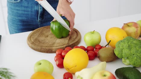 slices of green sweet pepper. the girl cuts pepper with a knife in the kitchen