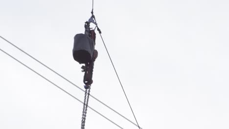 tools are hoisted up on cable to electrical maintenance technician on pylon