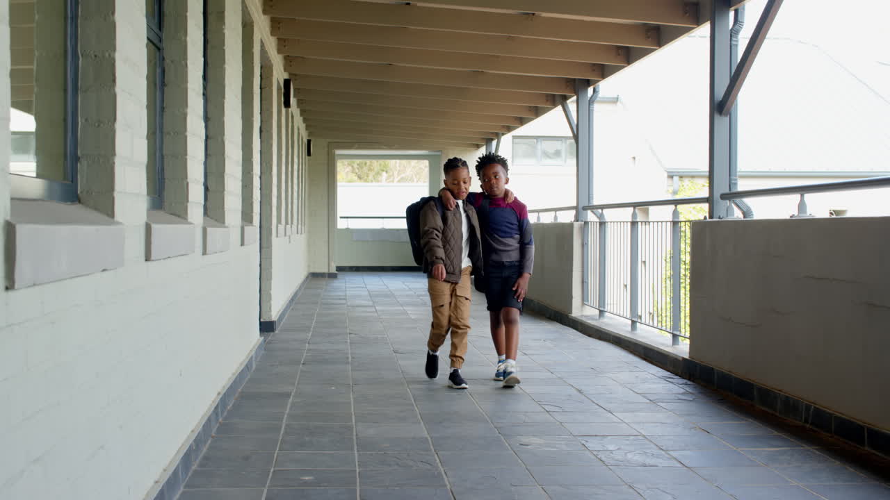 multiracial boys walking together in school hallway, enjoying friendship