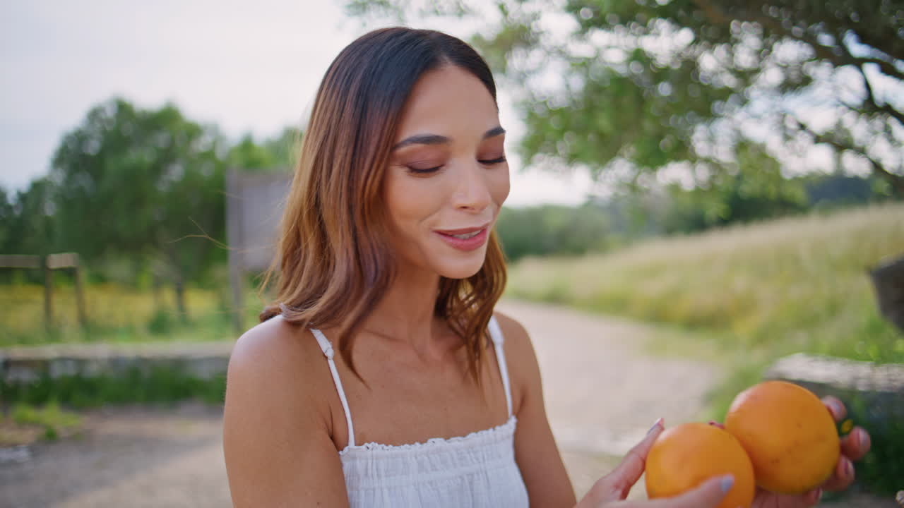 Gentle woman smelling orange summer courtyard closeup. Brunette enjoying siesta