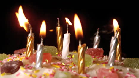 velas de cumpleaños encendidas en el pastel con confeti cayendo en el fondo