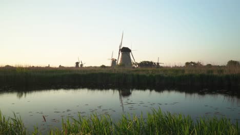 Molinos-De-Viento-Holandeses-En-El-Paisaje-Rural-Con-Lago-Temprano-En-La-Mañana