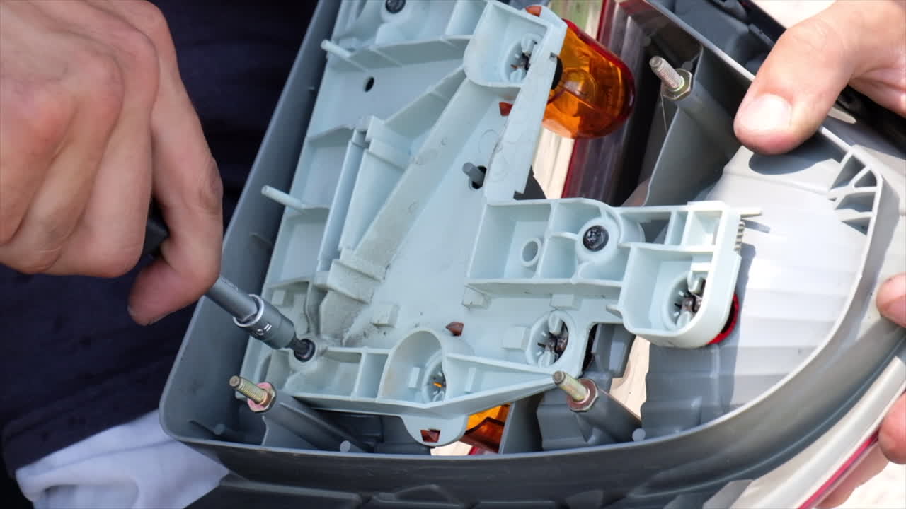 Close up of a man using a screwdriver to work on the headlight of a car