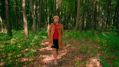 caucasian women with an overcoat and hat walking in the forest trail and enjoying the atmosphere