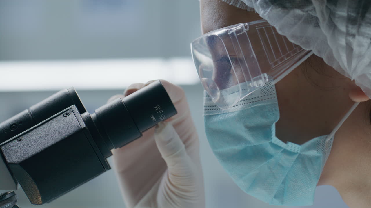 Scientist Viewing Sample through Microscope Eyepiece in Laboratory