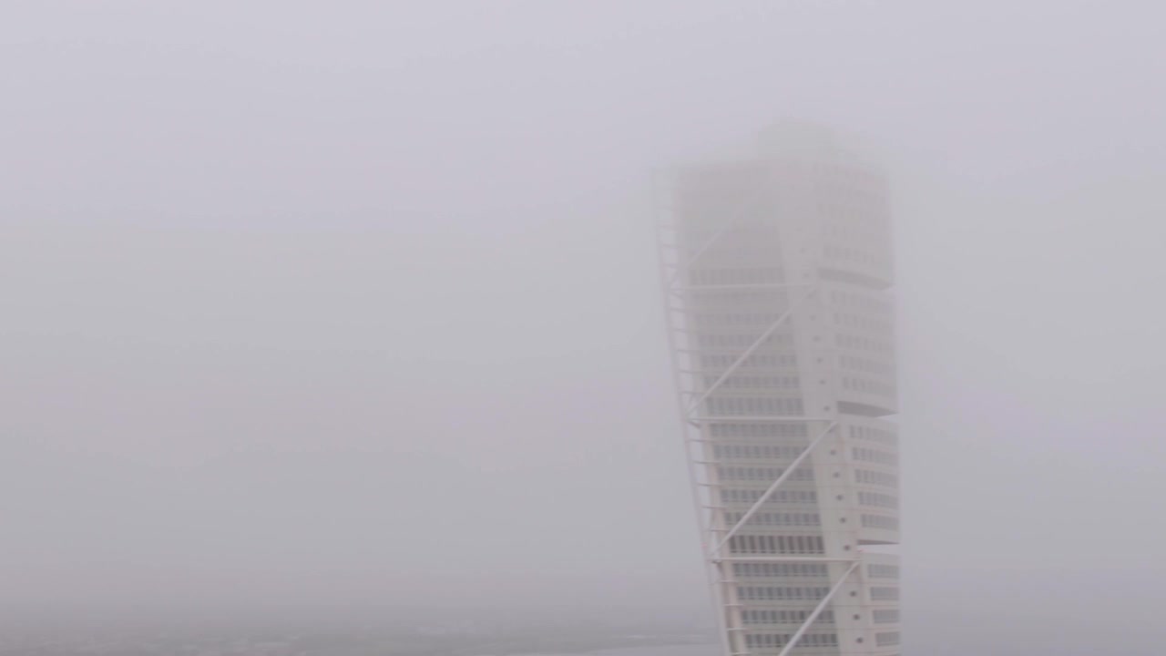 Dron aéreo del moderno edificio de apartamentos Turning Torso en Malmö y calles desapareciendo en una espesa niebla