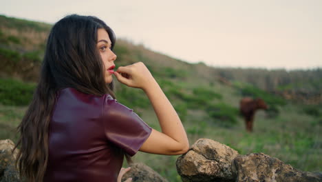 Dreamy-woman-posing-leaning-on-stone-fence-ar-gloomy-weather-alone-close-up.