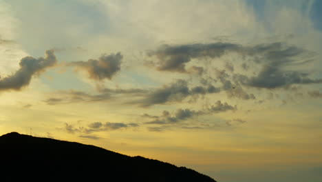 Static-Shot-Of-An-Orange-Sunset-With-A-Small-Plane-Disappearing-Into-The-clouds