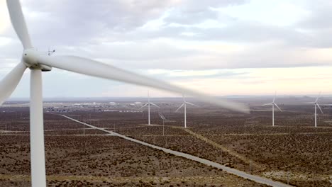 closeup propeller blades reveal into aerial shot across vast wind turbine farm landscape aerial dolly left