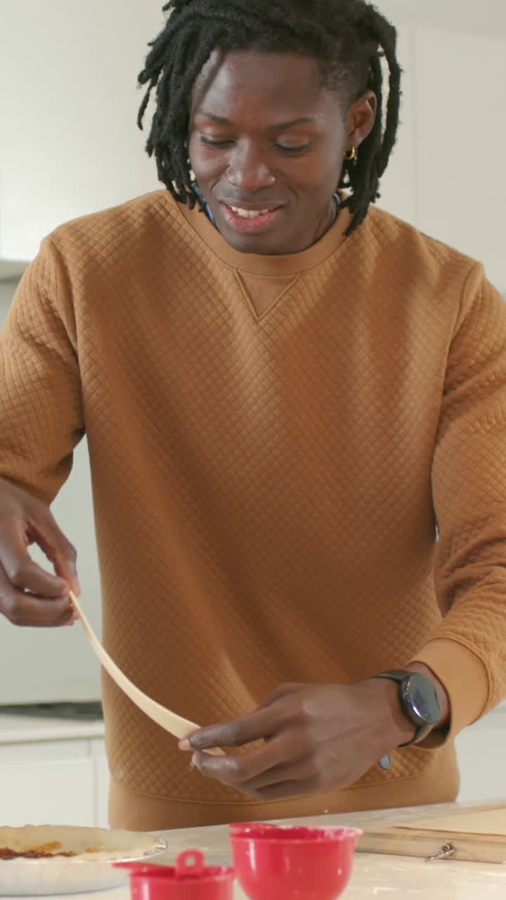 Vertical video: Testing dough, man in sweater stretching, placing on tart in kitchen making tart