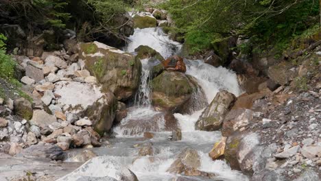fresh mountain water flowing downhill between rocks on sunny autumn day. swiss alps in fall season. aerial close up.