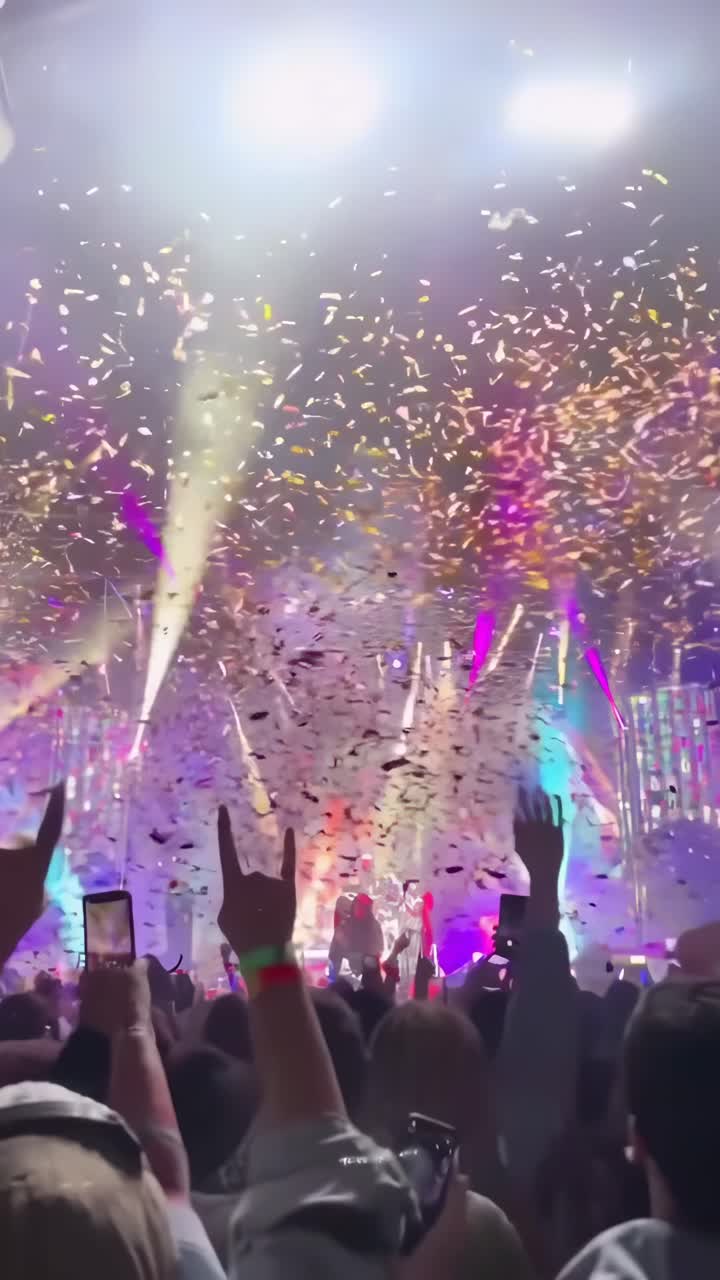 Video vibrante di un concerto con coriandoli, luci colorate e folla, ripreso da un'angolazione dal basso
