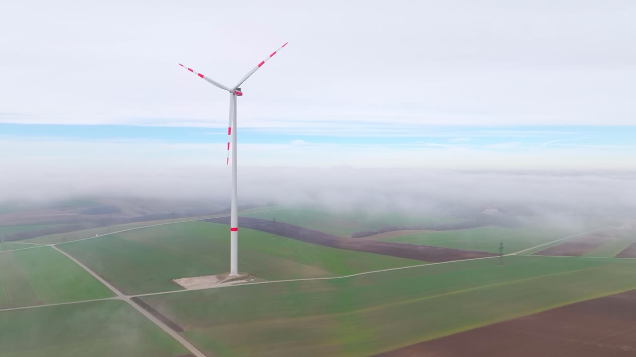 안개 날 농장에서 빨간 줄무를 가진 풍력 터빈