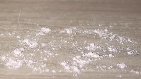 hands scattering flour over wooden table to make dough, close up