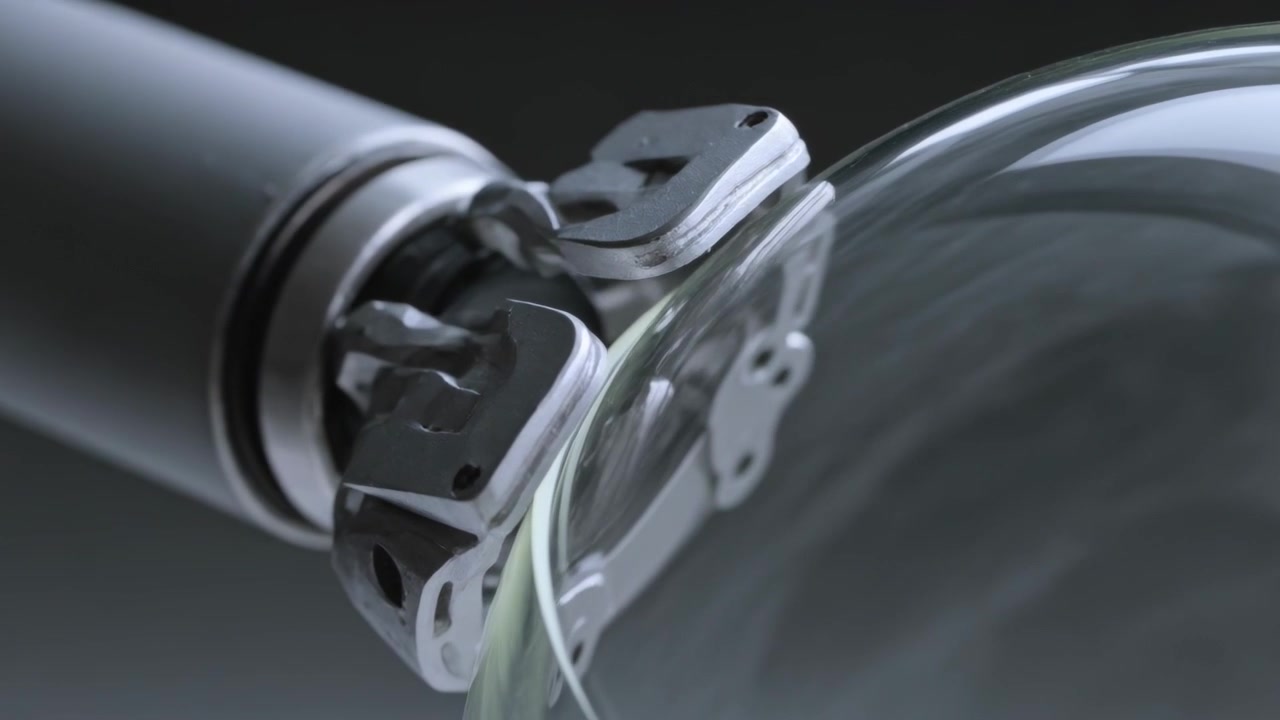 Rotating metal shaft guiding multi-plate clamp over clear glass dome in studio, fastener holes seen