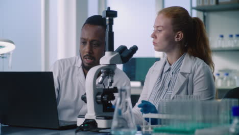 scientists collaborating in a modern laboratory with microscope and laptop