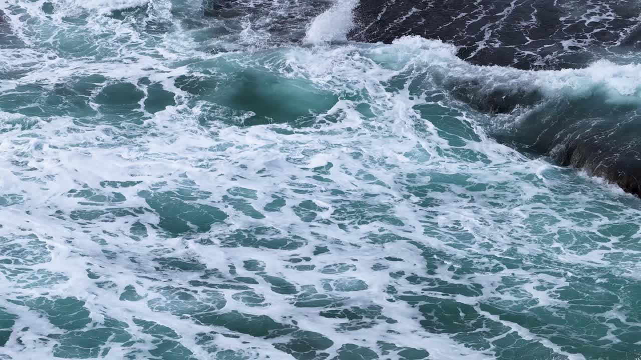 Dynamic ocean waves surge and crash on rocky coast, overcast daylight, medium static shot