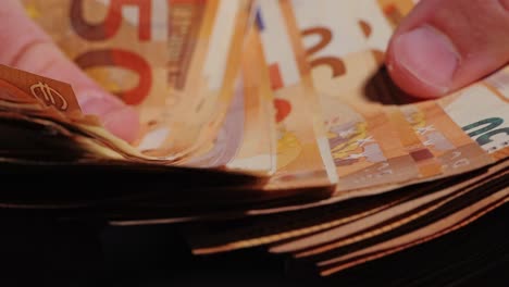 extreme close-up of fingers flipping through euro bills in dramatic hand motion