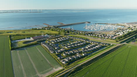 Aerial-View-Of-Water-Village-And-Roompot-Marina-Harbour-With-A-Distant-View-Of-Windmills-At-Neeltje-Jans-Nature-Reserve-In-The-Netherlands