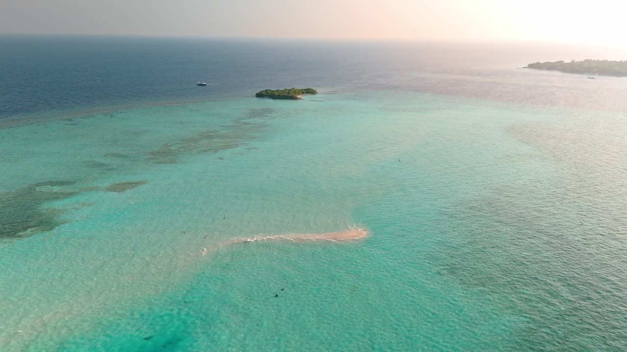 An awe-inspiring aerial drone view captures the Rasdhoo Sandbanks glowing under the soft, golden light of sunset in the Maldives.