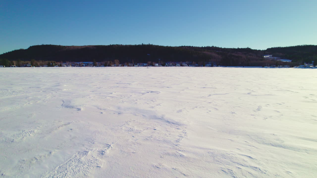 Máy bay không người lái bay phía trên một hồ đóng băng ở Canada, theo sau một xe trượt tuyết