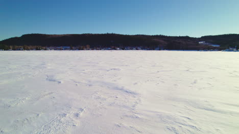 Flying-drone-above-a-frozen-lake-in-canada-following-a-snowmobile