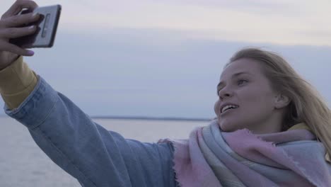 young woman make a selfie on autumn beach at phone