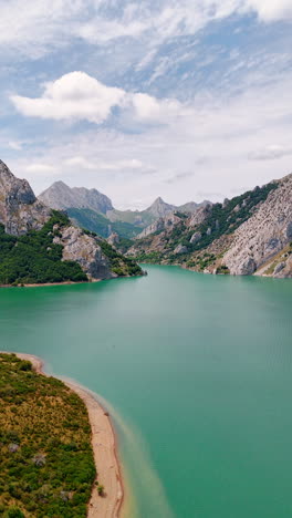 wild nature of spain, europe. drone footage over the turquoise lake surrounded by stunning mountains. vertical video.