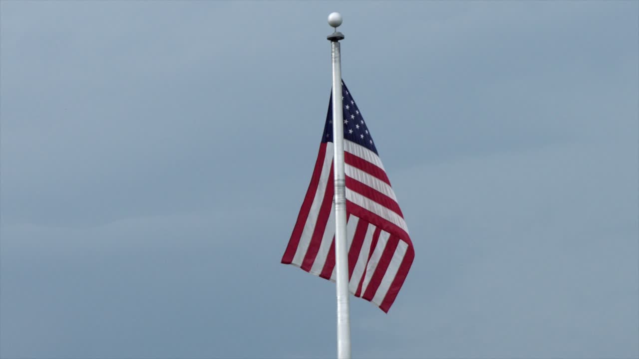 bandera americana en el asta de la bandera ondeando en el viento contra el cielo azul - cámara lenta
