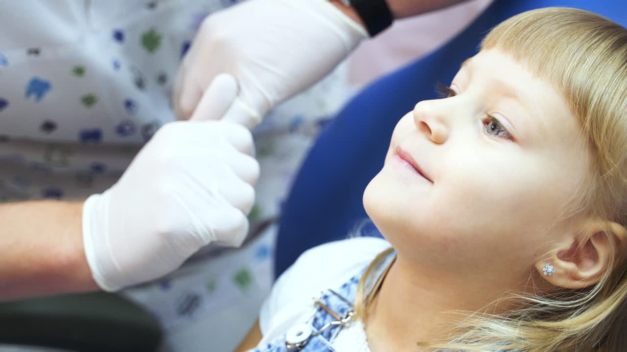 Little blonde girl with a visit to the dentist shows her teeth with her mouth wide open. Children's dentist